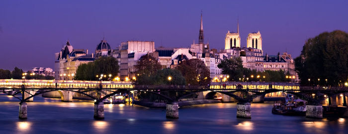 Bridge over river in city against sky at night