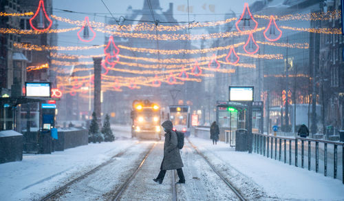 Woman walking on snow covered city street during winter