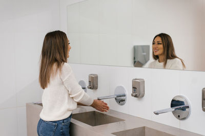 Women's hands under the water jet from the mixer. a middle-aged woman washes her hands 