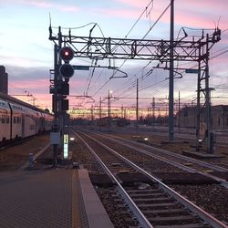 Railroad station platform against sky during sunset