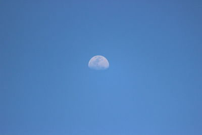 Low angle view of moon against blue sky