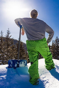 Rear view of man skiing on snow against sky