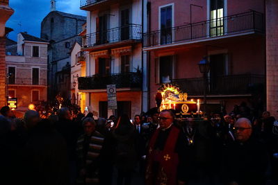 People on street against illuminated buildings at night