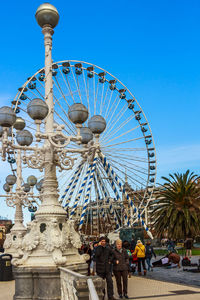 Ferris wheel in city against blue sky