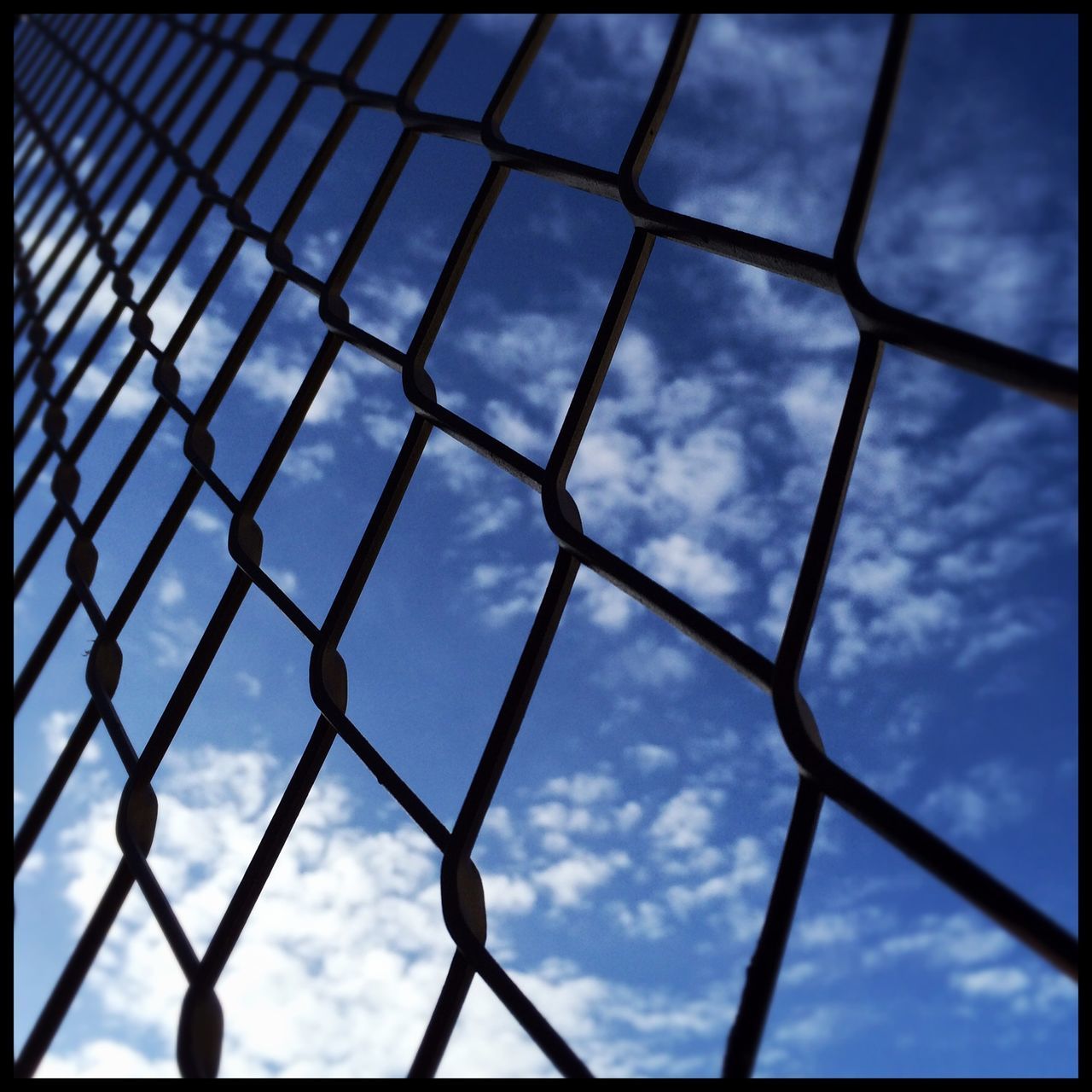 full frame, backgrounds, pattern, metal, low angle view, sky, transfer print, chainlink fence, protection, geometric shape, safety, cloud - sky, fence, day, grid, auto post production filter, blue, built structure, metallic, no people