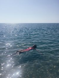 Man swimming in sea against clear sky
