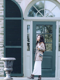 Full length of young woman standing against wall