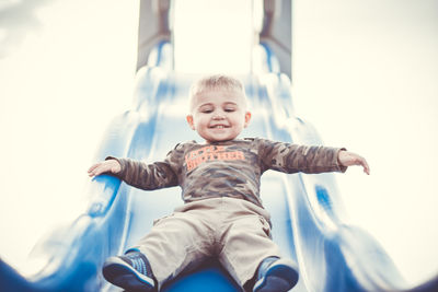 Cute boy sliding on slide at playground
