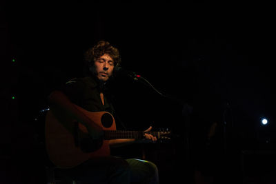 Young man playing guitar at night