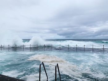 Swimming pool by sea against sky