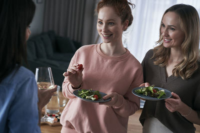 Smiling friends eating food while talking