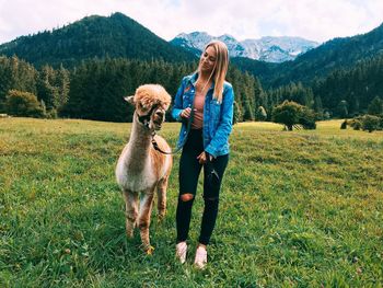 Smiling woman with llama standing on field