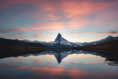 Scenic view of lake and mountains against sky during sunset