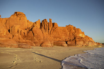 Rock formations by mountain against clear sky