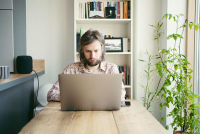 Young woman using phone while sitting on table at home