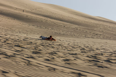 Man lying on sand at desert