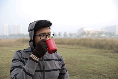 Portrait of man drinking coffee on field