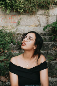 Portrait of young woman standing against trees