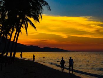 Silhouette people on beach during sunset