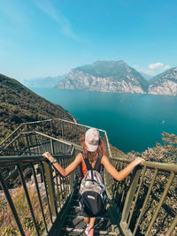 Rear view of woman sitting on railing against mountains