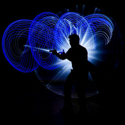 Silhouette of man with light painting at night