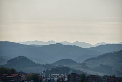 Scenic view of townscape by mountains against sky