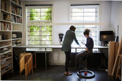 Full length of female architects discussing at table in office