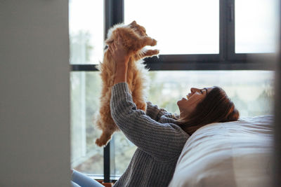 Cat sitting on a man looking at window