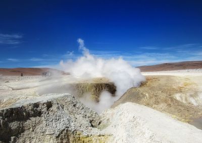 Scenic view of volcanic mountain against blue sky