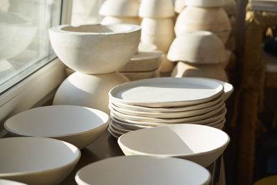 Stack of crockery on table by widow