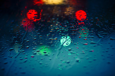 Close-up of water drops on multi colored lights