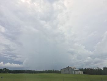 Scenic view of grassy field against cloudy sky