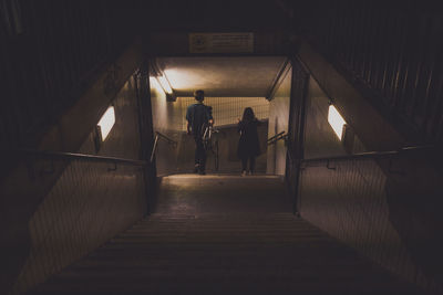 Rear view of man and woman walking in underground walkway