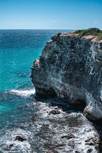 Rocks on sea shore against blue sky