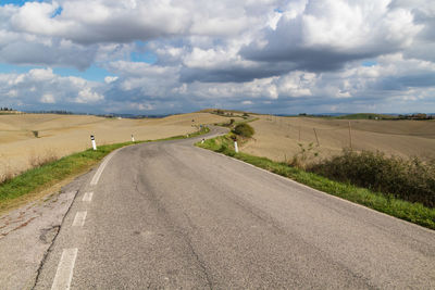 Road amidst field against sky