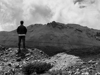 Rear view of man standing on mountain against sky