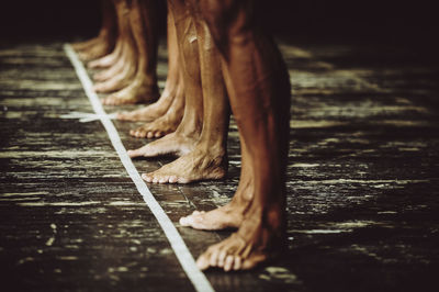 Low section of men standing in row on wooden floor