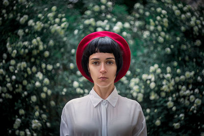 Portrait of young woman standing against plants at park