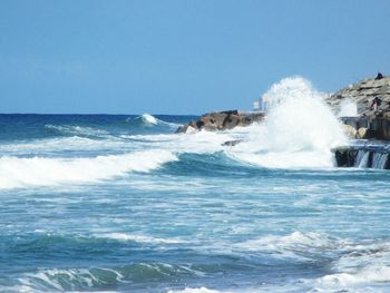 Waves splashing in sea against clear sky