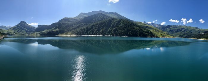 Scenic view of lake and mountains against blue sky