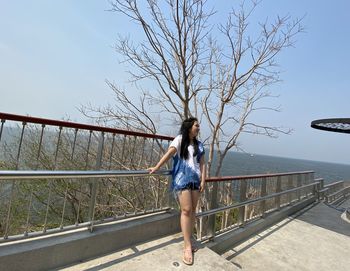 Full length of woman on footbridge against sky