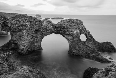 Rock formations on sea shore against sky