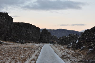 Road leading towards mountains against sky