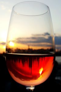 Close-up of beer glass against orange sky