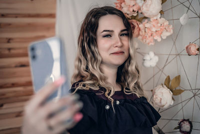 Portrait of smiling young woman standing against wall