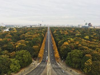 Road amidst plants and trees against sky in city