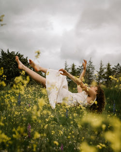 Woman on field by trees against sky