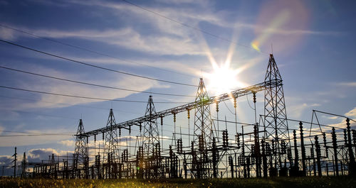 Low angle view of electricity pylon against sky during sunset