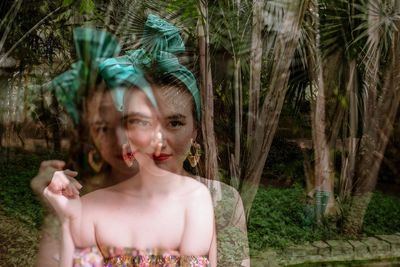 Double exposure image of beautiful woman against trees in park