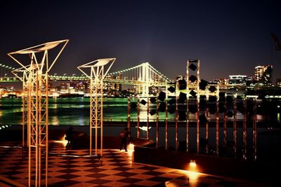 People in illuminated city against sky at night